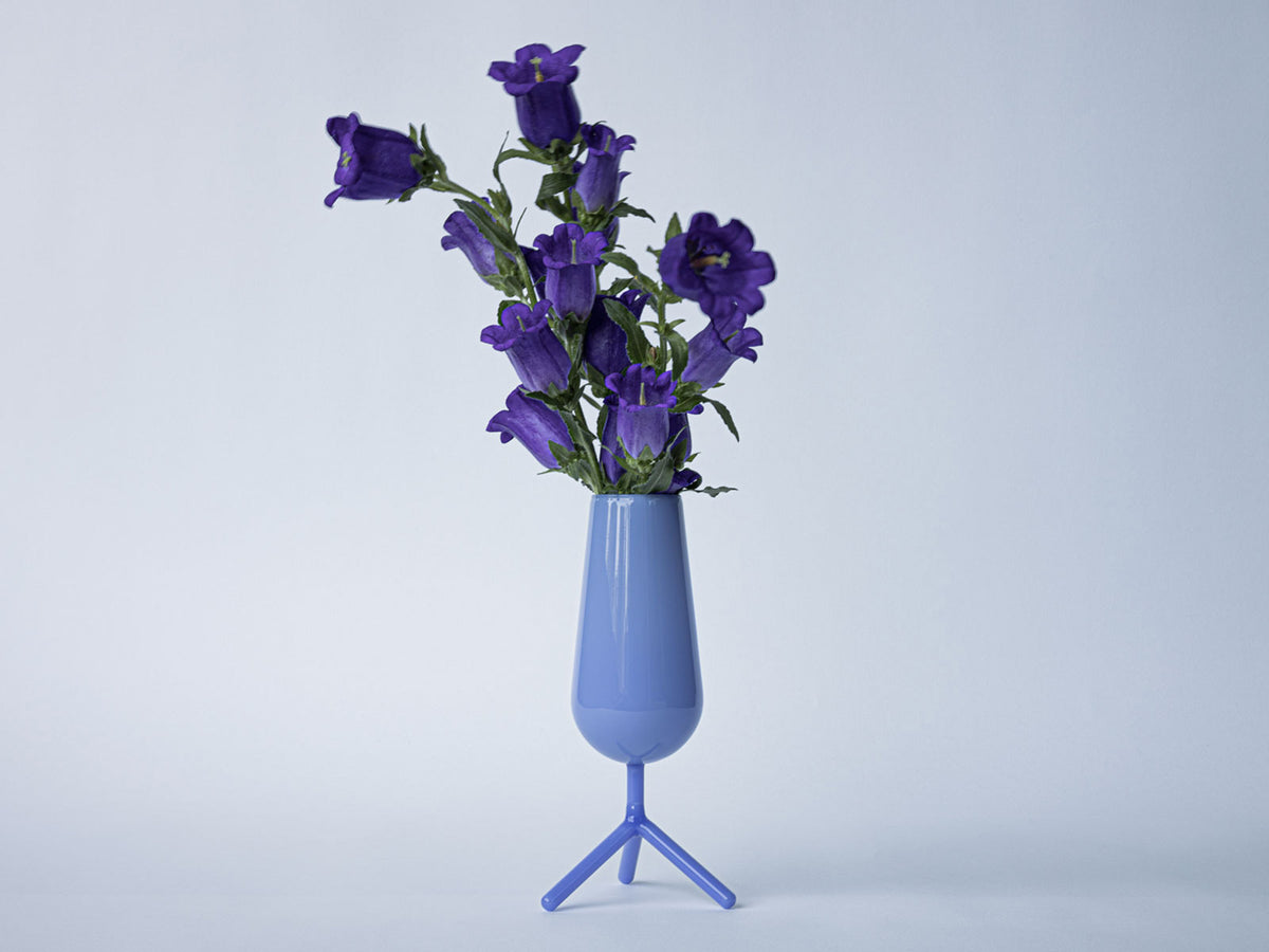 Kleine vaas in lavendelblauw glas op driepootvoet, gevuld met paarse bloemen