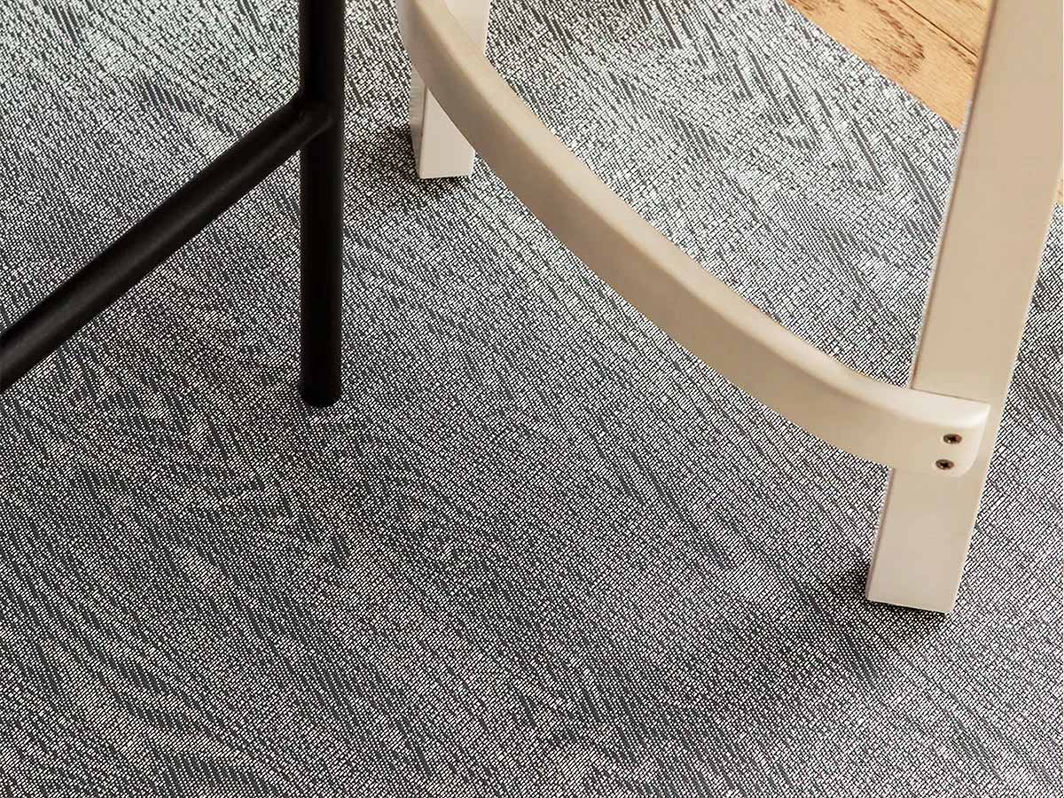 Chilewich Woodgrain vloerkleed in Slate, detail met stoelpoten erop