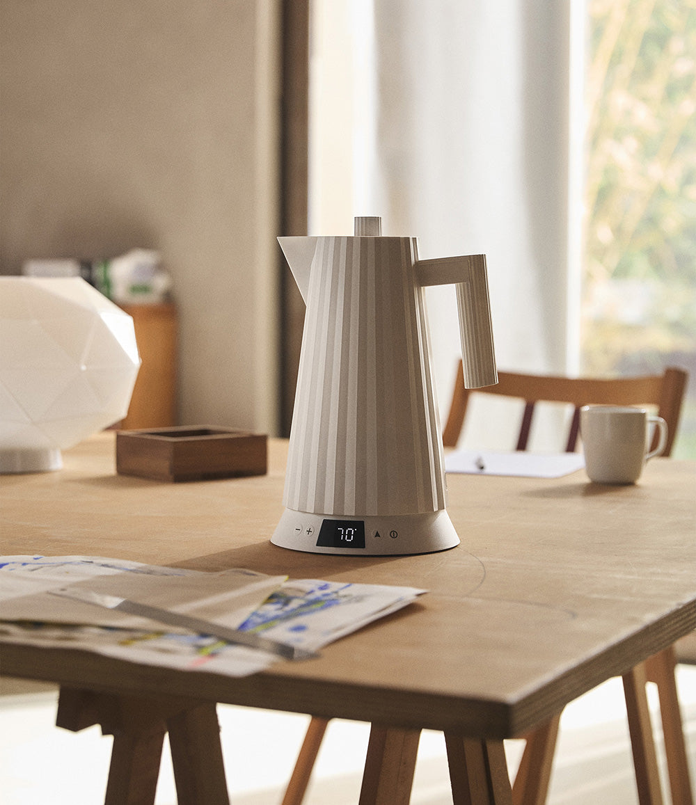 Plissé waterkoker in wit, geplaatst op een houten tafel