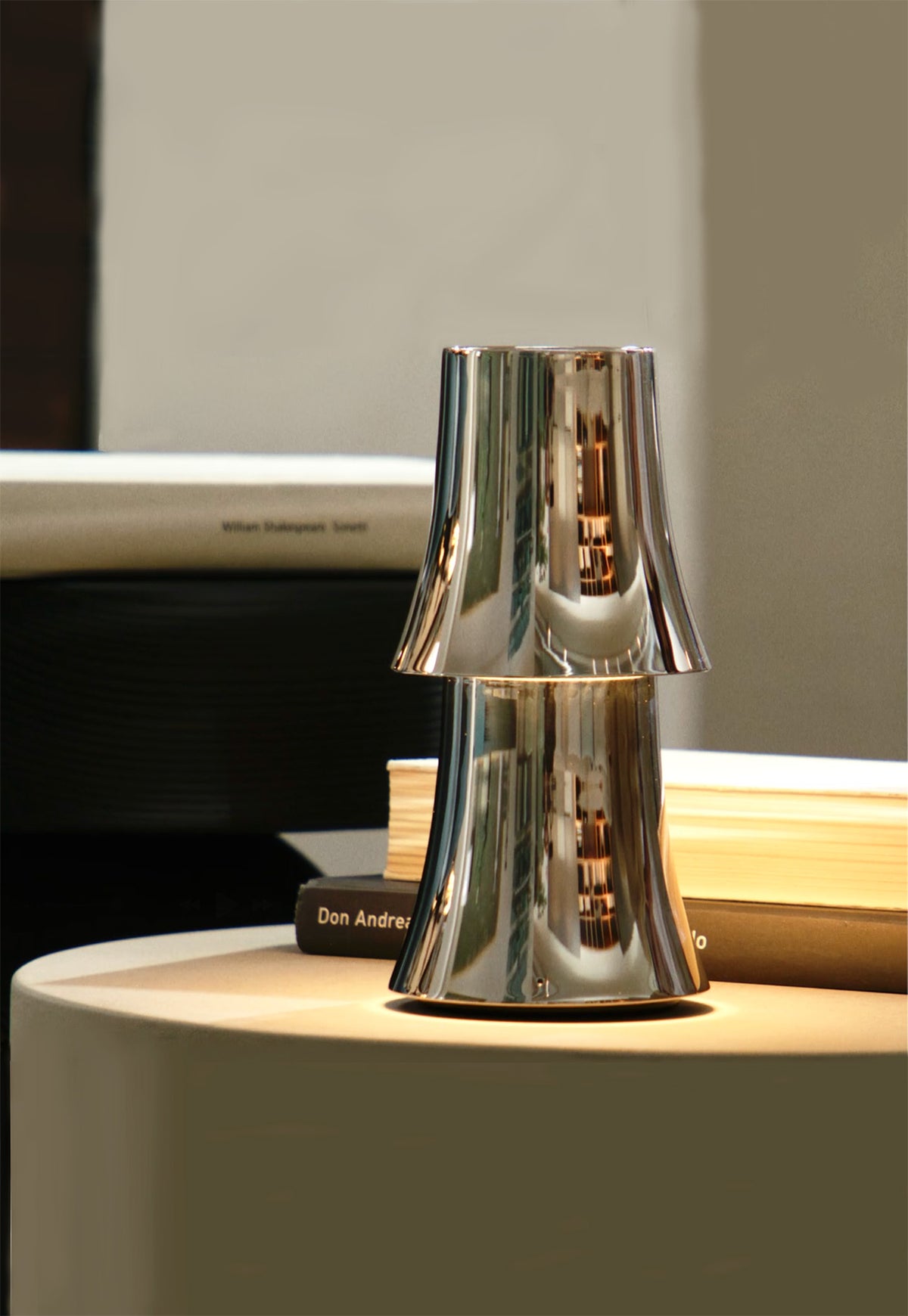 Halesia tafellamp van Alessi, ontwerp van Michael Anastassiades, in chroom op tafel met brandend licht