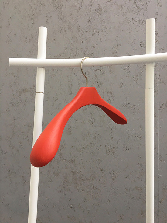Amo kledinghanger in rood, hangend aan een garderobestandaard
