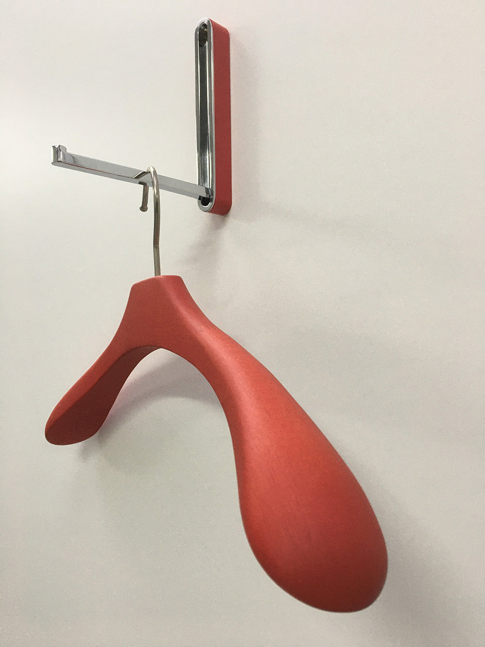 Amo kledinghanger in rood, bevestigd aan wandbeugel met haak