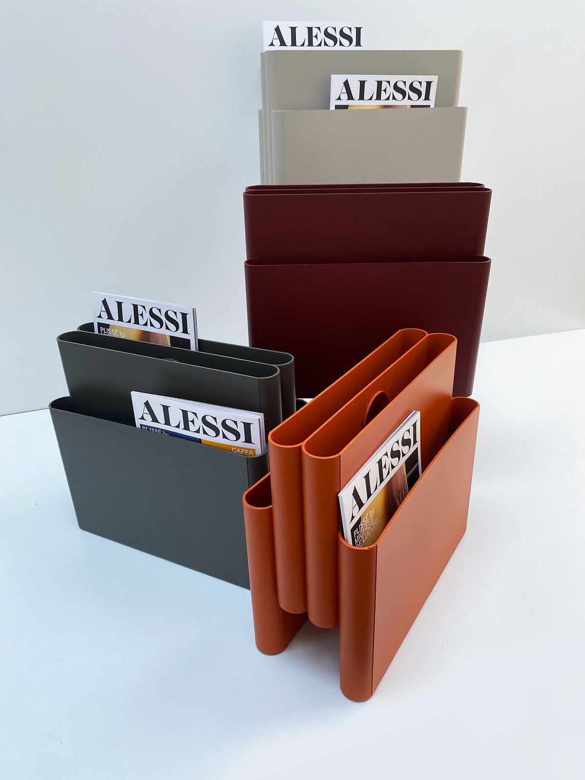 Kartell tijdschriftenrek in grijs, bordeaux, antraciet en oranje naast elkaar