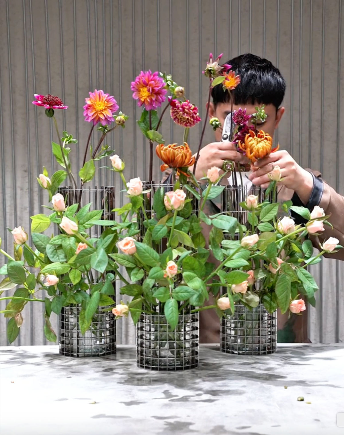 Meerdere grote Gravity-vazen met bloemen, tijdens het schikken.