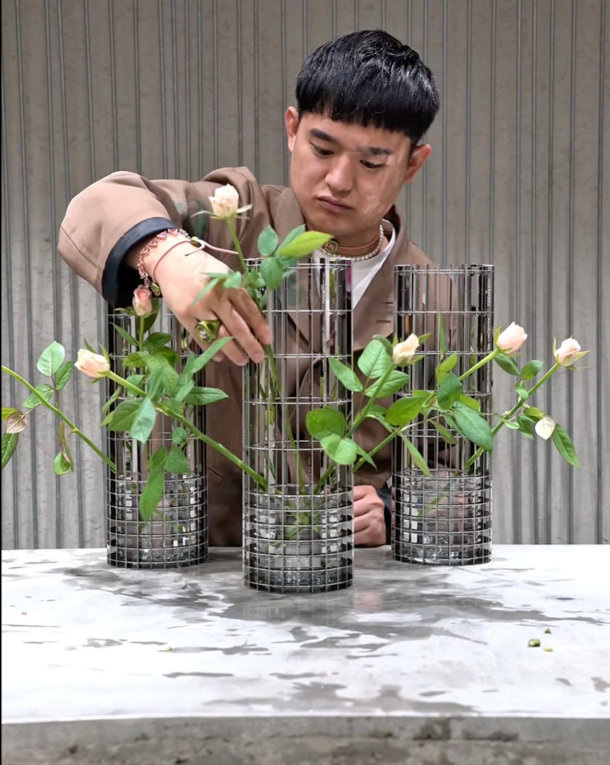 Persoon schikt bloemen in drie grote Gravity-vazen van Fundamental.