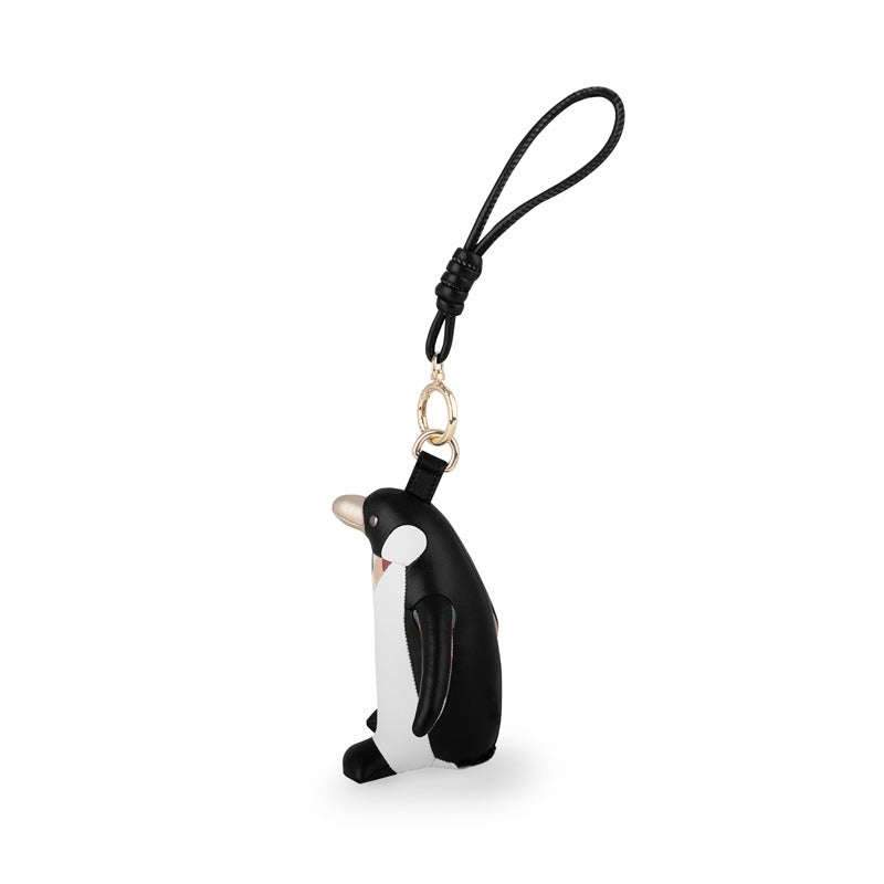 Zijaanzicht van de Zuny pinguïn tassenhanger, zwart-wit kunstleer met gouden clip.
