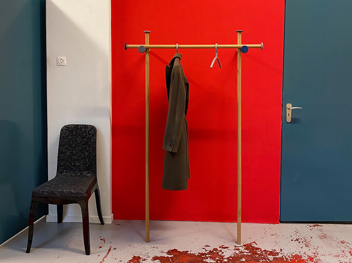 Wooden leaning coat stand in use, jacket hung over crossbar