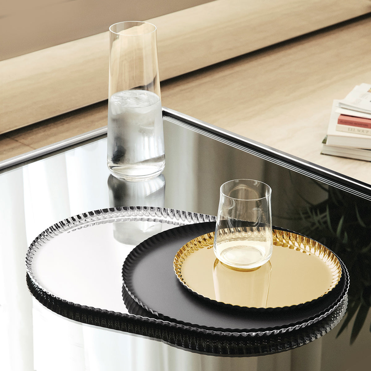 Ronde dienbladen uit de Pleats-serie van Alessi naast elkaar in zwart, zilver en goud.