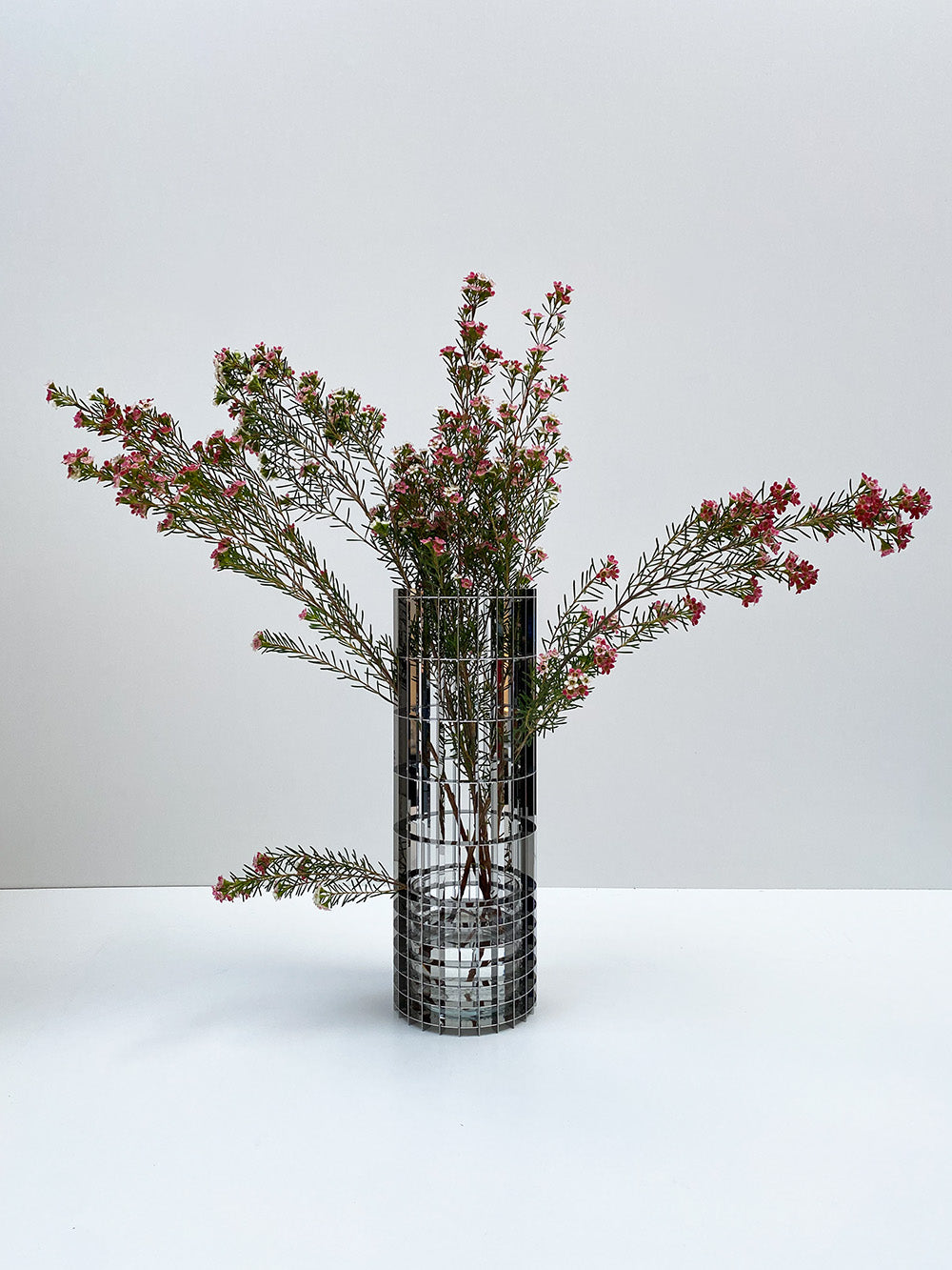 Grote vaas uit de Gravity-serie van Fundamental, gegridde glasstructuur met bloemen.