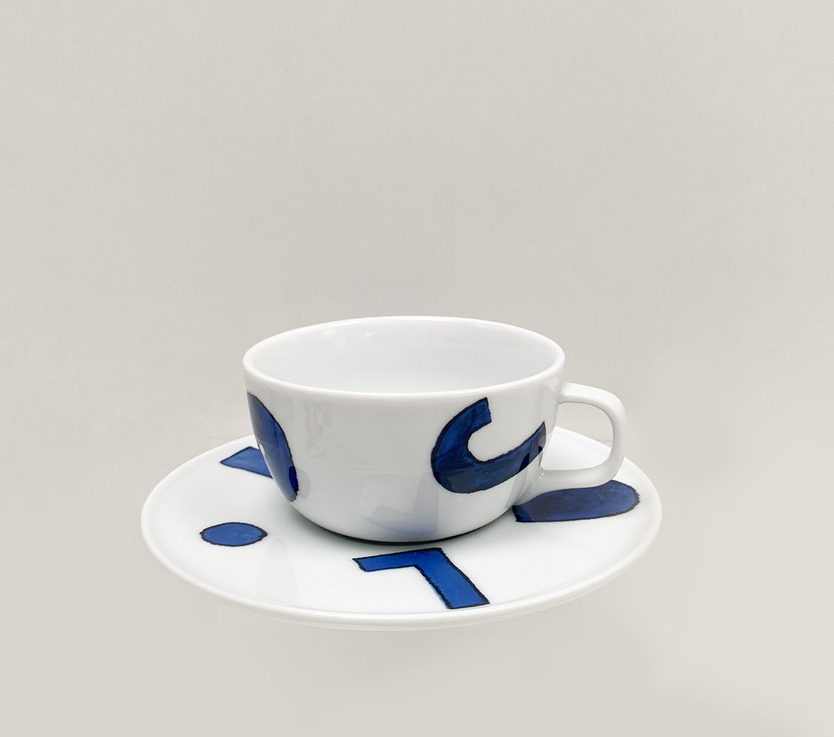 Theekop met schotel, decor yunoki, zijaanzicht in wit porselein met blauwe motieven.