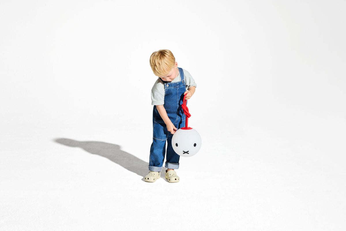 Kind draagt de fatboy Bolleke lamp aan het rode ophanglusje