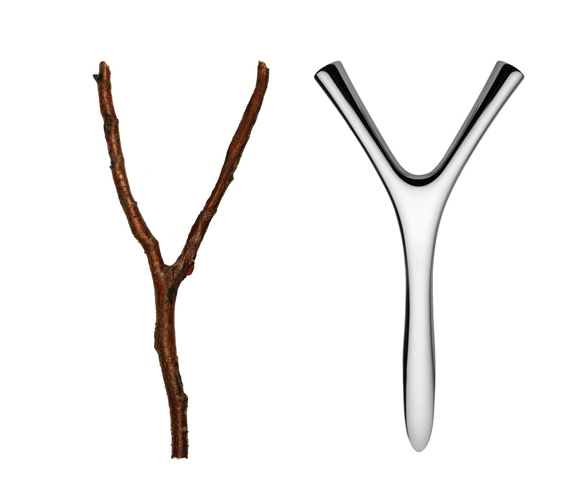 Virgula Divina crown cork opener in stainless steel, design Frédéric Gooris, next to branch