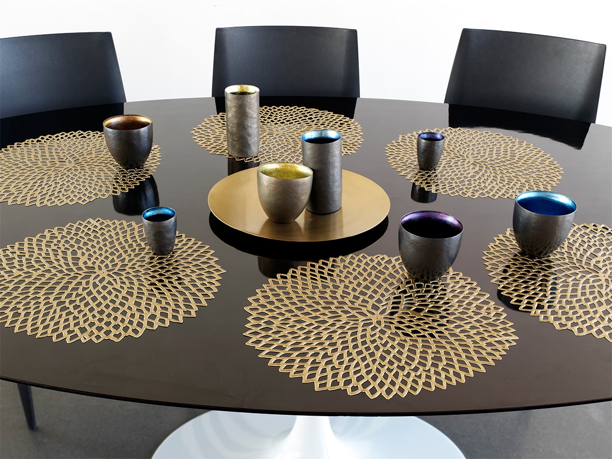 Chilewich Dahlia Brass placemats op een tafel, meerdere placemats met servies erop