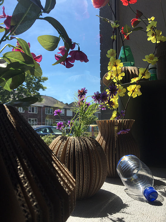 Cache-Cache Diamant kartonnen vaas naast andere kartonnen vaasvormen, met bloemen