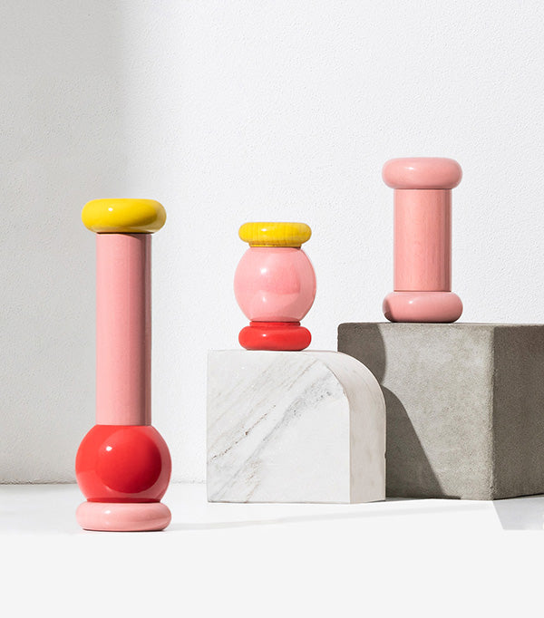 Three Twergi pepper mills by Alessi in rose-red and pink, with yellow and red details
