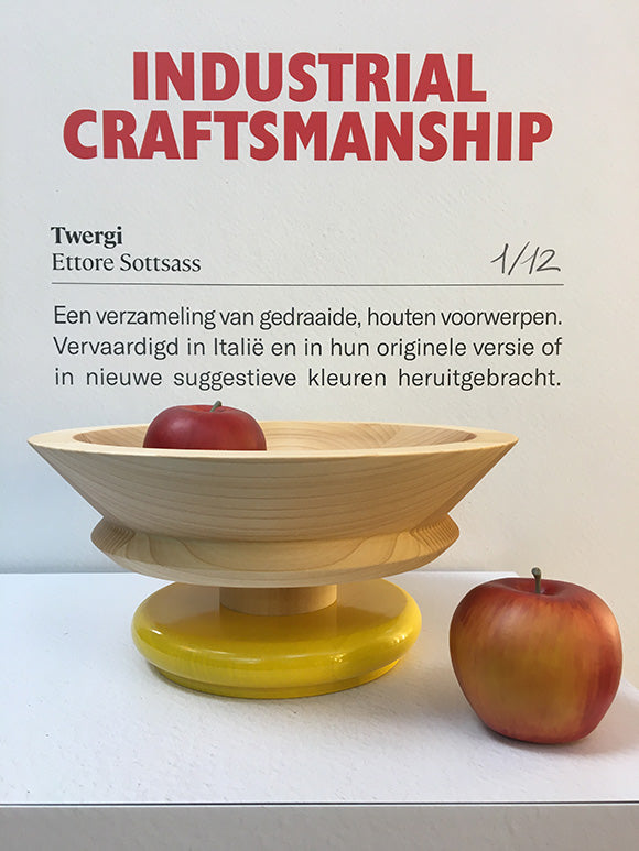 Alessi Twergi fruitschaal in blank hout met gele basis, met appels ernaast.