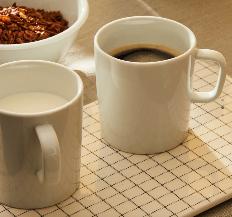 Twee Platebowlcup mokken naast elkaar, gevuld met koffie en melk
