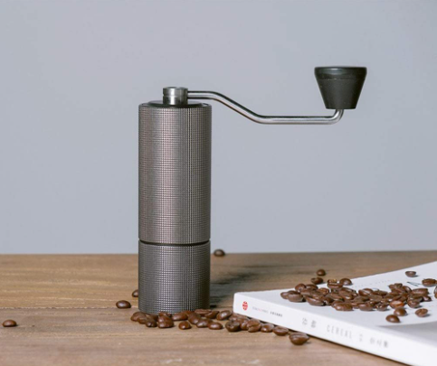 Alessi koffiemolen C2 in antraciet, staand naast koffiebonen