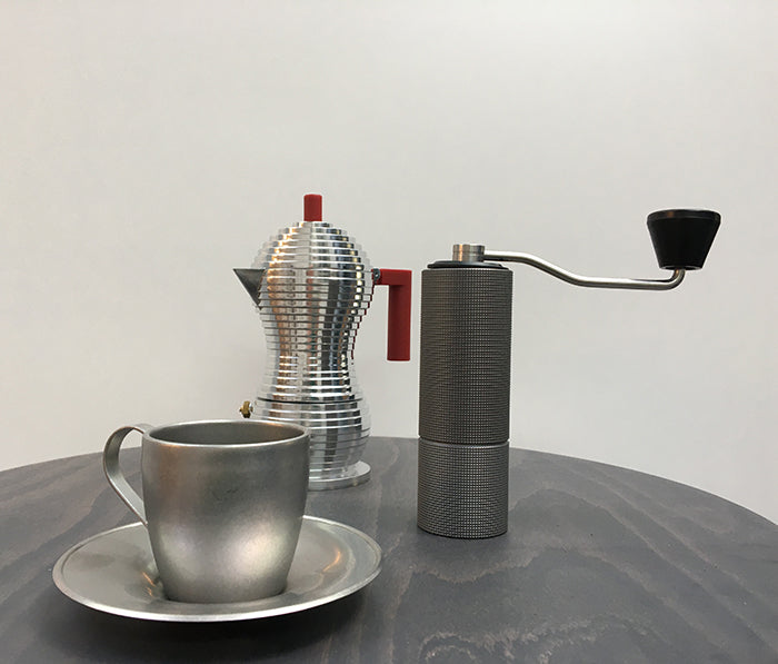 Alessi koffiemolen C2 in antraciet naast espressomaker en kopje
