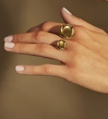 Acta-ring van Alessi in goud, close-up aan de hand met twee cirkels