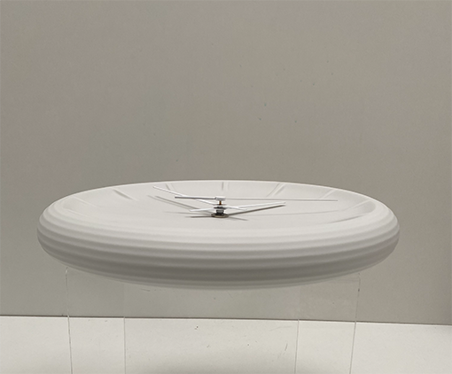 Relief-keramische wandklok in wit, liggend, met zicht op de geribbelde rand