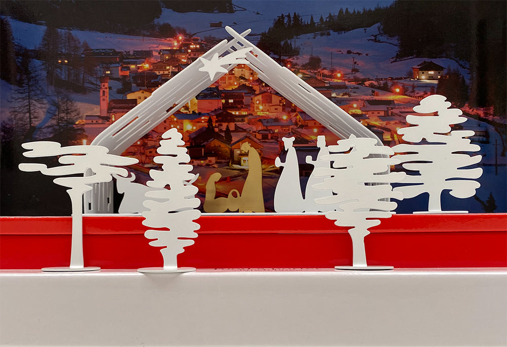Alessi Bark witte boompjes en kerststal, opgesteld op rode ondergrond.