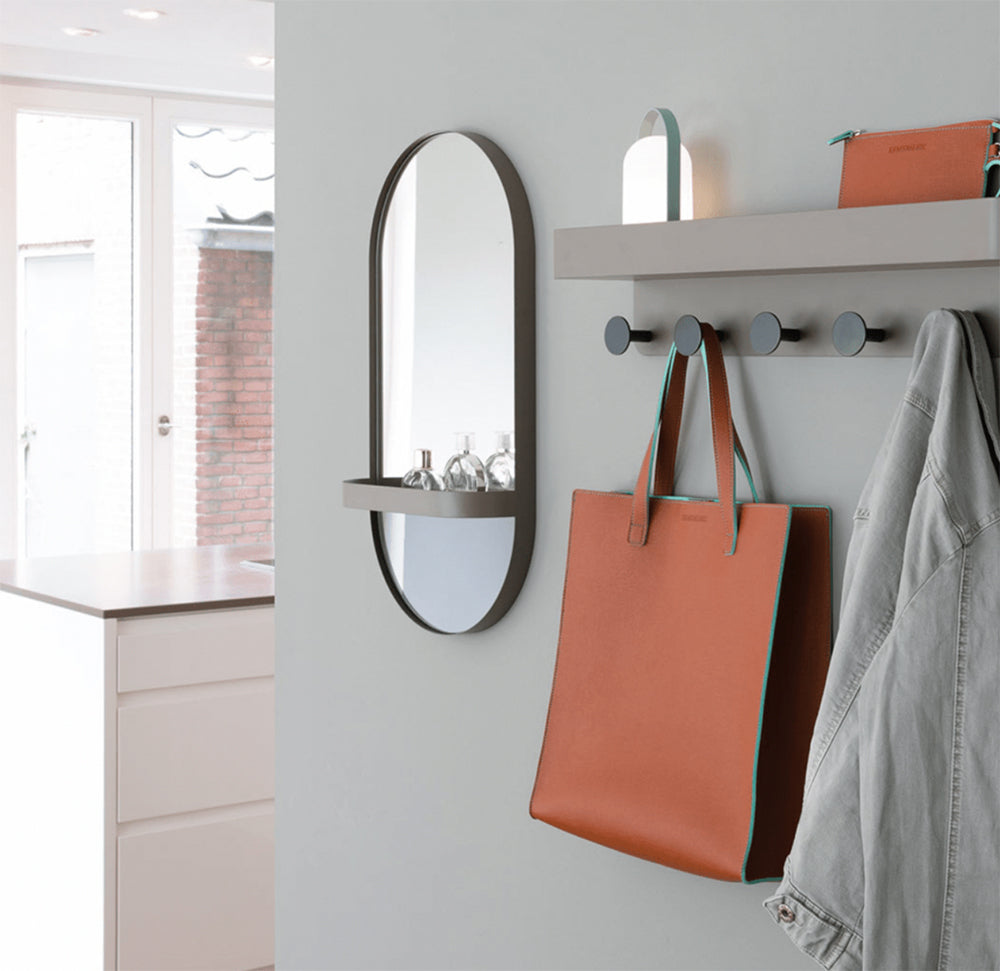 Spiegel van taupe staal aan de wand in een gang, met wandgarderobe