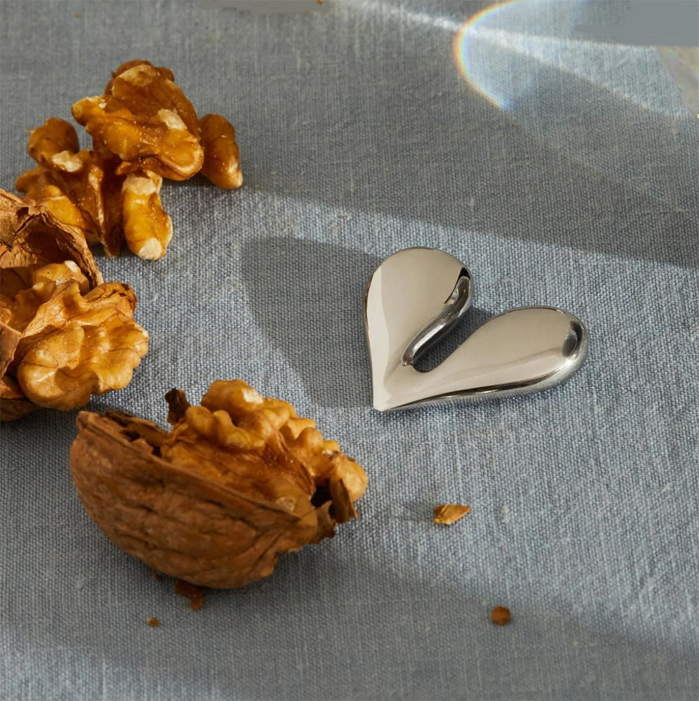Alessi Nut Splitter naast een opengebroken walnoot, hartvormig, klein formaat