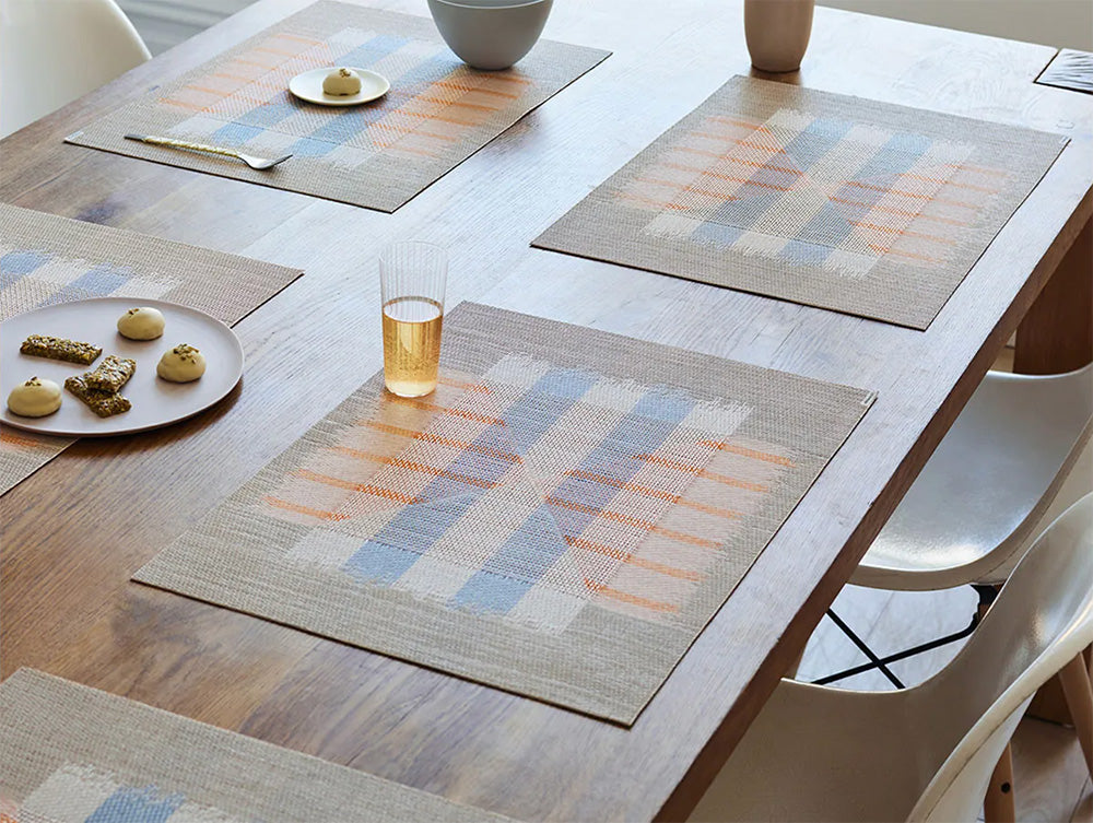 Meerdere Mesa Opal placemats van Chilewich in gebruik op een tafel, lichtblauw-oranje ruitpatroon