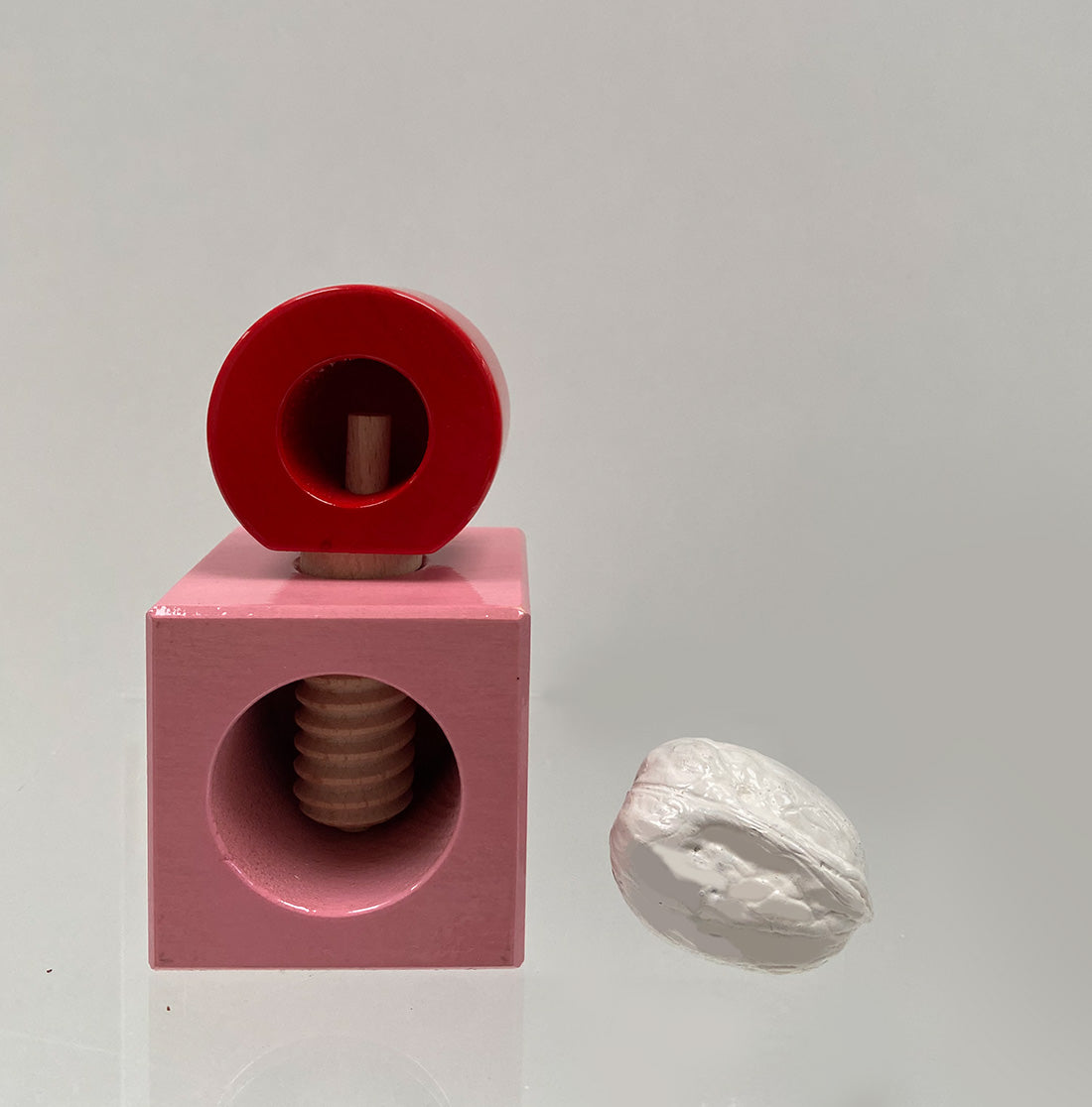 Vooraanzicht met geopende onderkant van de Alessi Twergi notenkraker in rood en roze