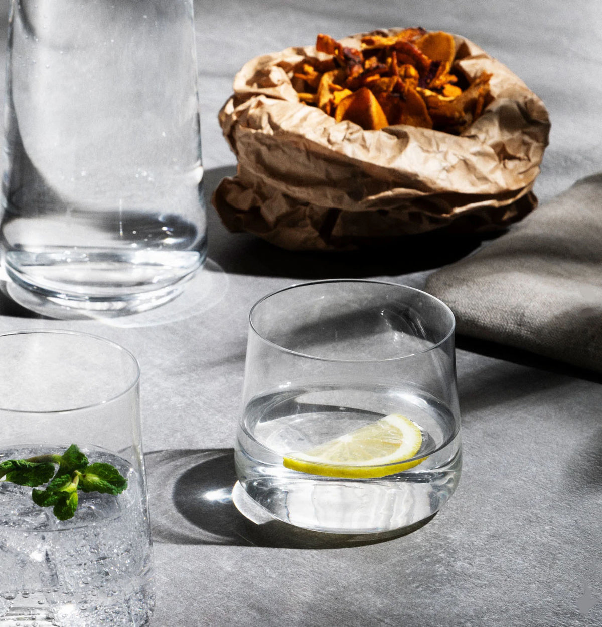 Alessi Eugenia waterglas, gevuld met drank en schijfje citroen