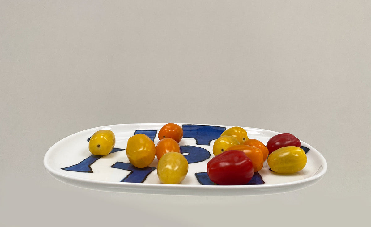 Ovaal serveerbord uit de Itsumo-serie, wit met blauw motief, met tomaatjes erop