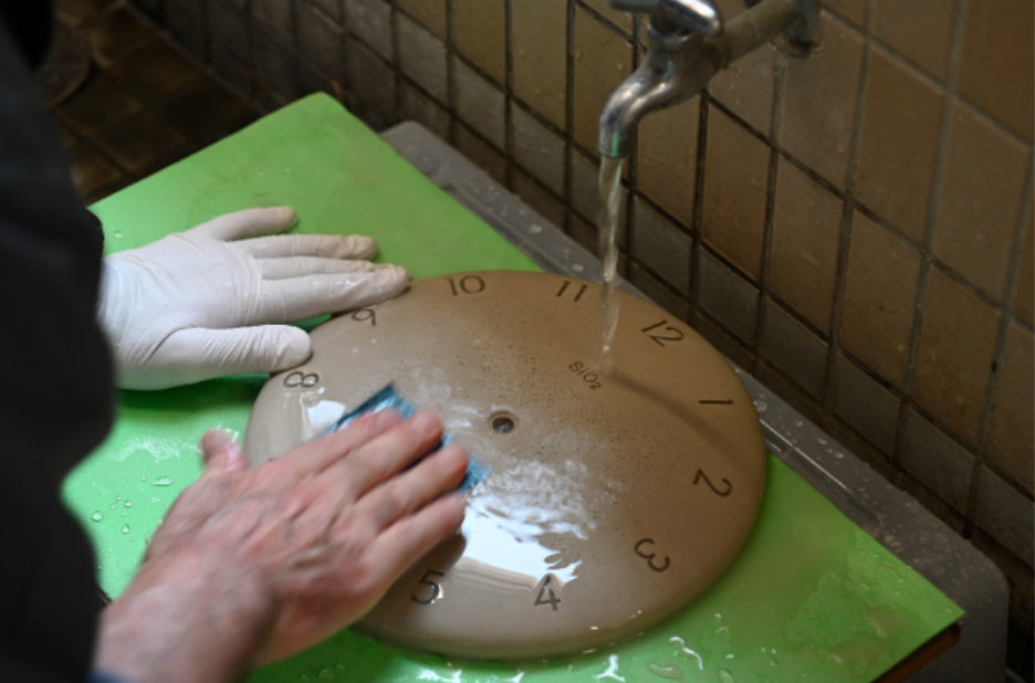 Handmatige speciale behandeling van de Lemnos SIO2 wandklok tijdens productie.