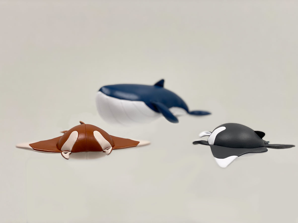 Zuny Manta Mito presse-papier naast andere kleurvarianten en een walvisfiguur