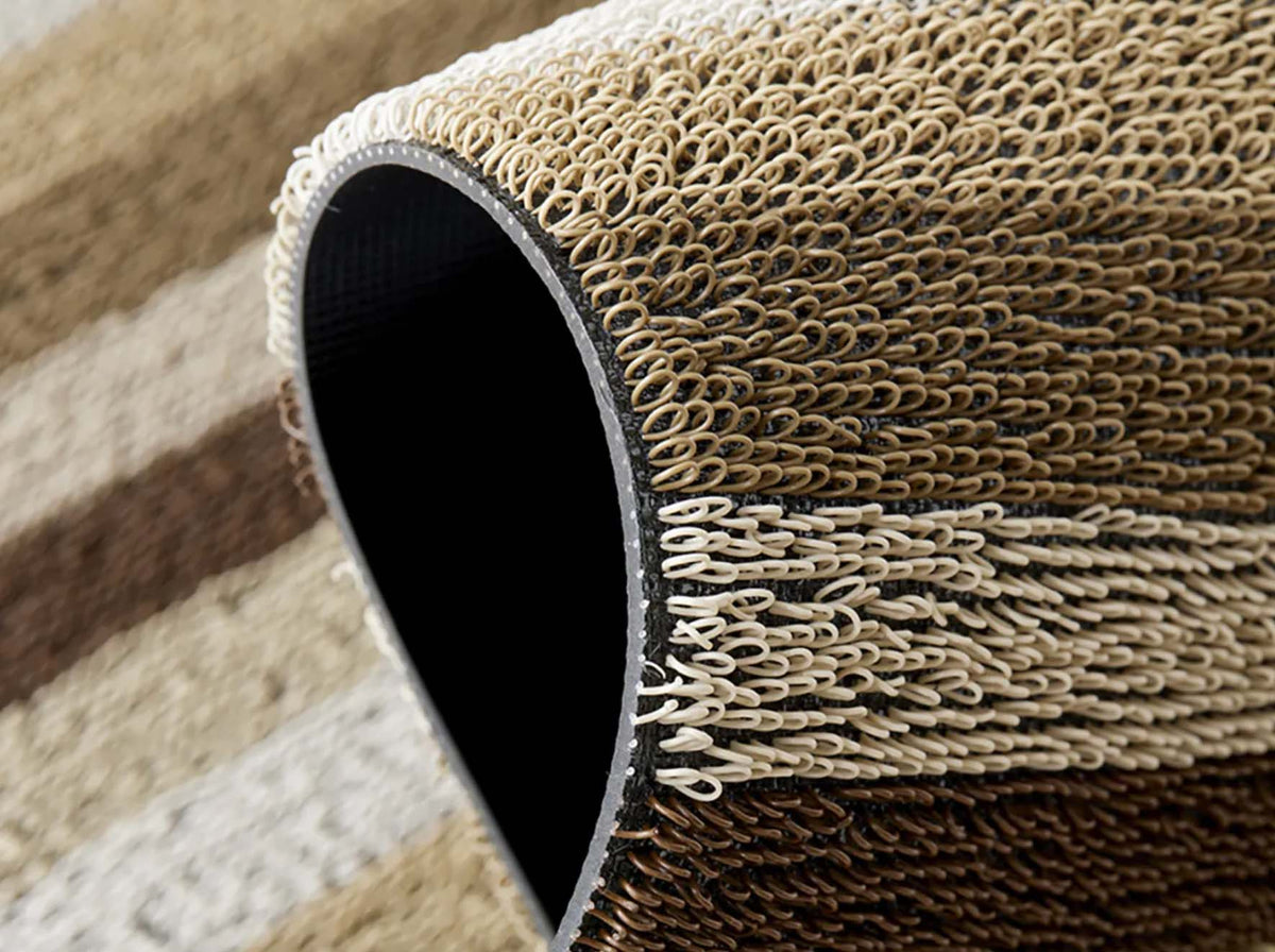 Detail van deurmat Even Stripe Mocha, opgerold met getufte structuur in bruin en beige