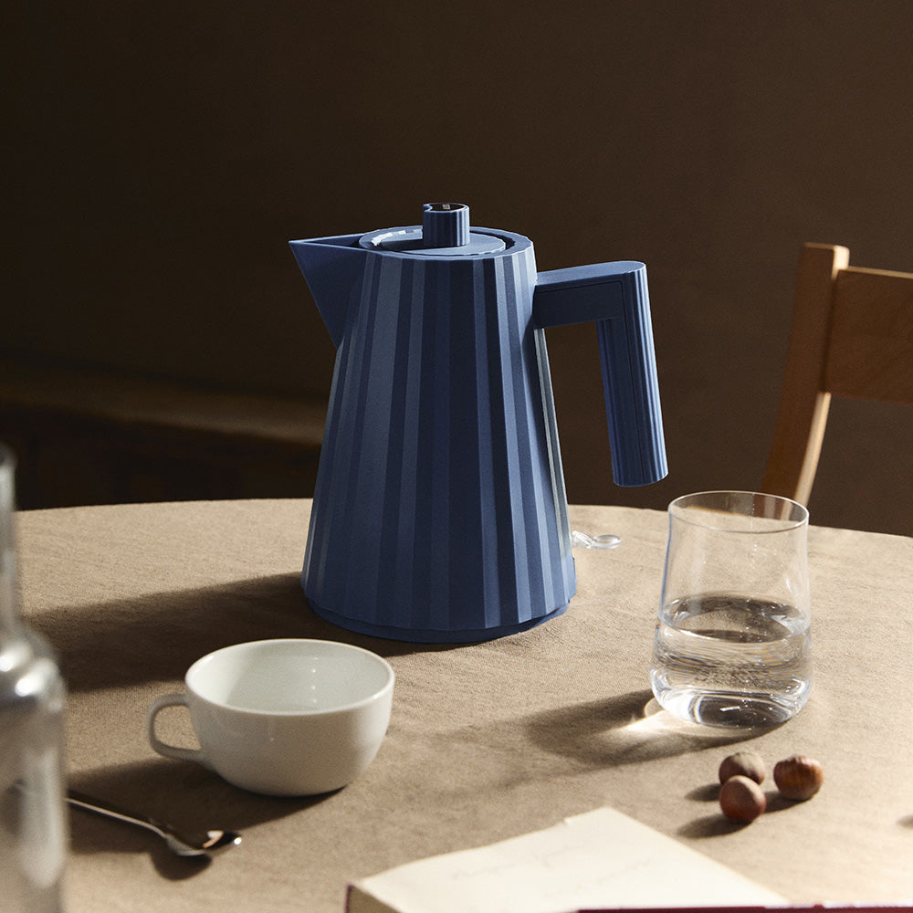 Plissé waterkoker in blauw, detail van kan en handvat naast kop en glas