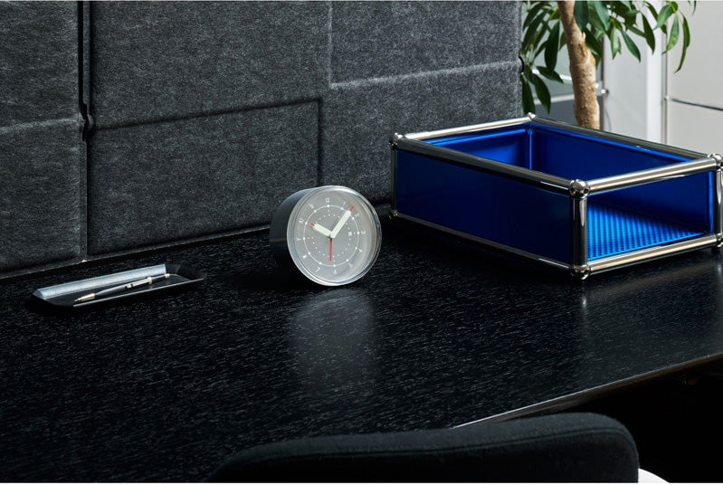 Alessi Ento analoge wekker, aluminium, rond model op een bureau