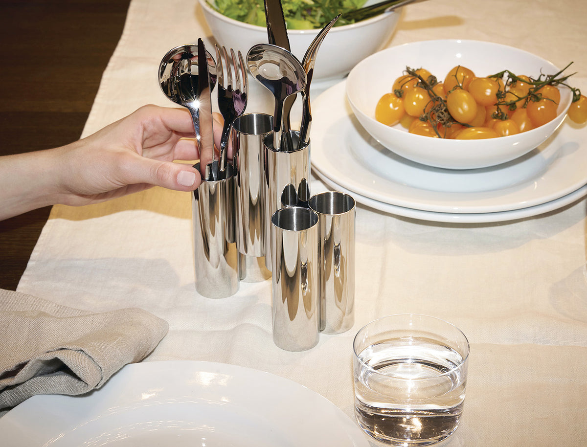 Hand pakt bestek uit de Alessi Canale bestekhouder