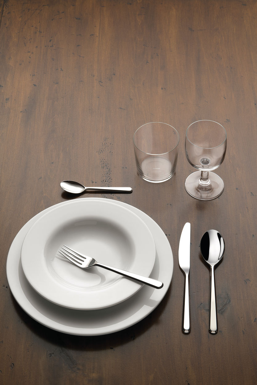 Amici bestek van Alessi naast bord en glazen