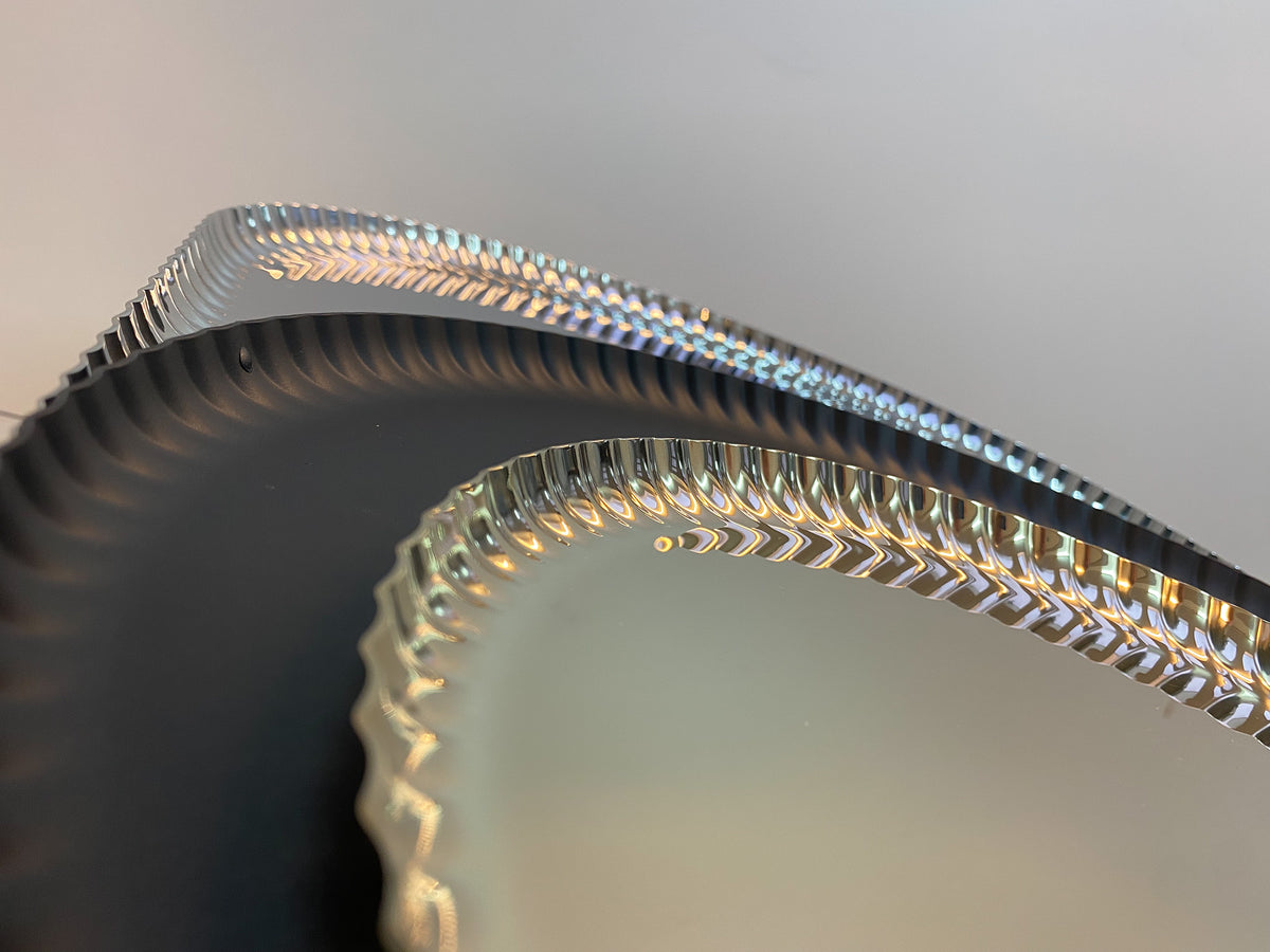 Detail van de geplooide rand van het ronde Pleats-dienblad van Alessi in zwart.