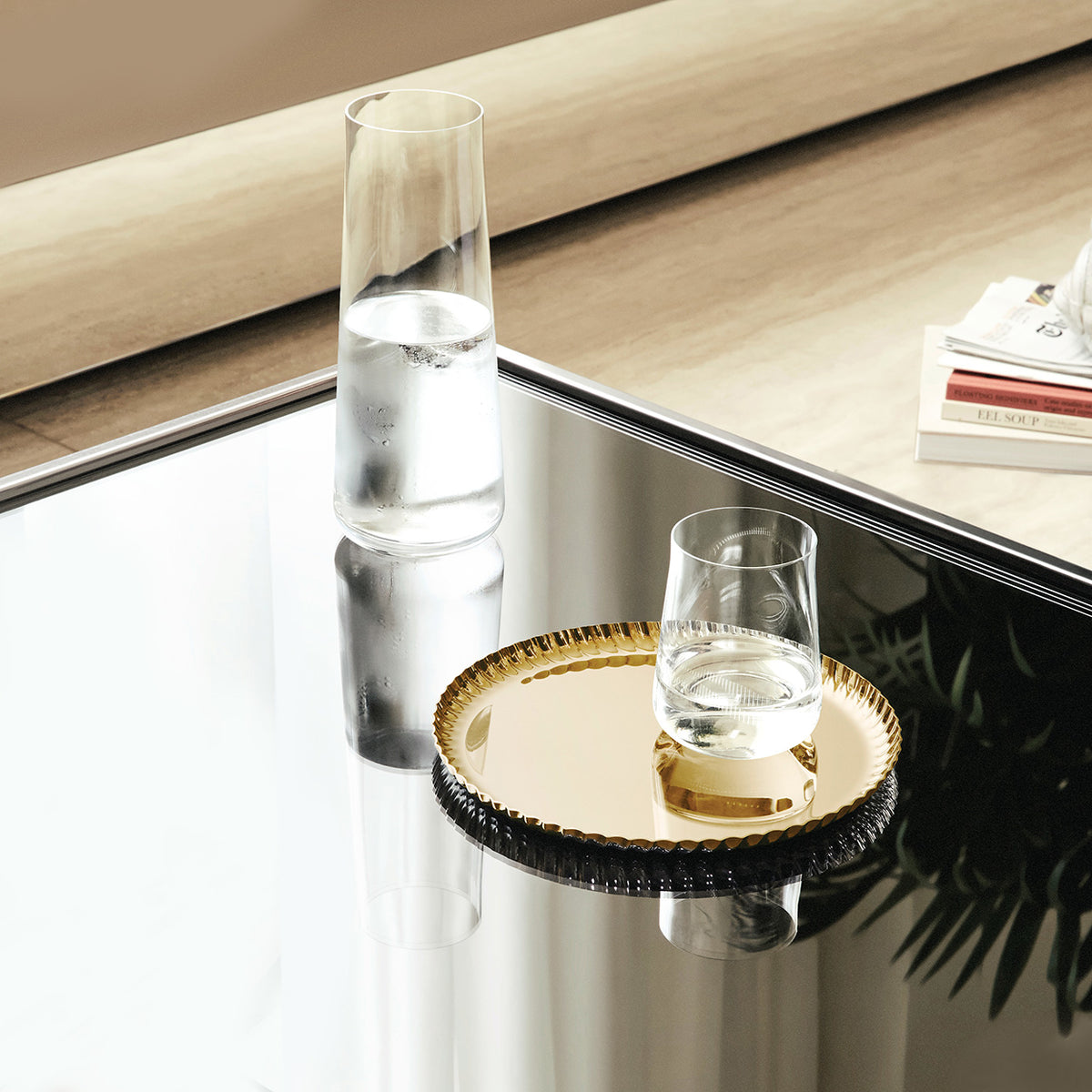 Rond Pleats-dienblad in witgoud met een glas water erop.