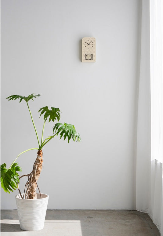 Lemnos MOOV cuckoo clock in ivory, metal case with perforations, hanging on wall