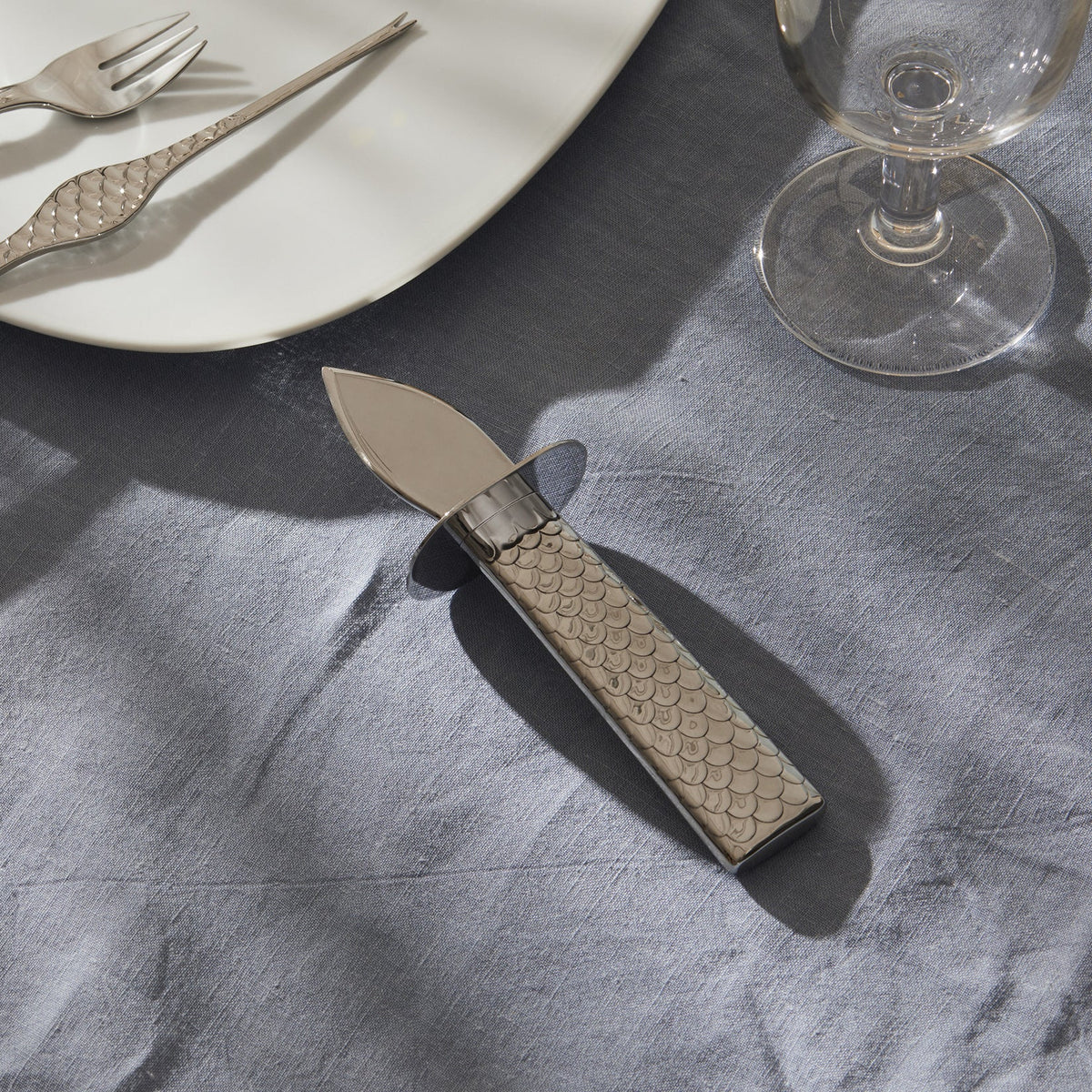 Alessi Colombina oestermes in staal, handvat met visschubmotief op tafel